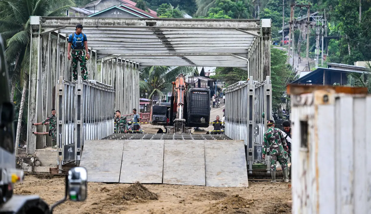 Seorang personel Tentara Nasional Indonesia (TNI) memeriksa bagian baru jembatan di atas sungai setelah jembatan tersebut rusak akibat banjir di Juli, provinsi Aceh, pada Minggu 14 Desember 2025. (CHAIDEER MAHYUDDIN/AFP)