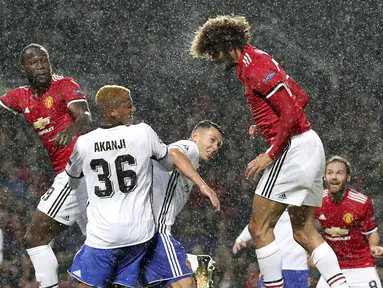 Sundulan pemain Manchester United, Marouane Fellaini (kanan) menembus pertahanan pemain Basel pada laga grup A Liga Champions di Old Trafford, Manchester, (12/9/2017). MU menang 3-0. (Martin Rickett/PA via AP)