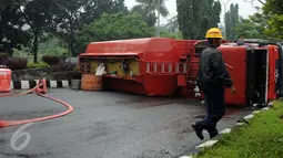 Petugas melintas di depan truk tangki BBM yang terbalik di ruas Jalan Tegar Beriman Kabupaten Bogor, Jumat (15/4/2016). Truk tangki bermuatan 24.000 liter BBM jenis premium terbalik sekitar pukul 05.00 dini hari. (Liputan6.com/Helmi Fithriansyah)