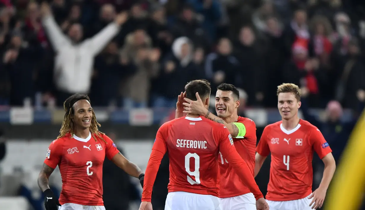 Haris Saferovic dan Granit Xhaka merayakan gol pertama timnas Swiss pada laga Nations League yang berlangsung di stadion Swiss porarena, Senin (19/11). Timnas Swiss menang 5-2. (AFP/Fabrice Coffrini)
