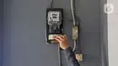 Warga memeriksa meteran listrik di kawasan Matraman, Jakarta, Kamis (2/4/2020). Di tengah pandemi COVID-19, pemerintah menggratiskan biaya tarif listrik bagi konsumen 450 Volt Ampere (VA) dan pemberian keringanan tagihan 50 persen kepada konsumen bersubsidi 900 VA. (Liputan6.com/Herman Zakharia)