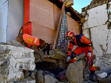 Seorang petugas penyelamat bersama dengan anjing pelacak mencari korban selamat di sebuah rumah setelah gempa bumi di kota Cuoguo, Shigatse, wilayah Tibet, Tiongkok barat daya pada tanggal 8 Januari 2025. (CNS/AFP/China OUT)