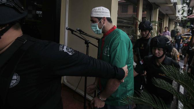 Artis Claudio Martinez memakai masker dengan tangan di borgol usai rilis narkoba di Polres Jakarta Barat, Jumat (9/11). Claudio ditangkap dengan barang bukti 7,96 gram ganja. (Liputan6.com/Faizal Fanani)