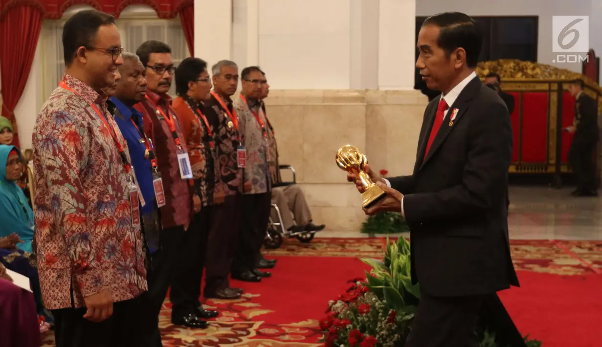 Presiden Jokowi memberi piala kepada Gubernur DKI Jakarta Anies Baswedan dalam acara silaturahmi dengan penerima manfaat Jaminan Kesehatan Nasional (JKN) dan Kartu Indonesia Sehat (KIS) di Istana Negara, Jakarta (23/5).(Liputan6.com/Angga Yuniar)