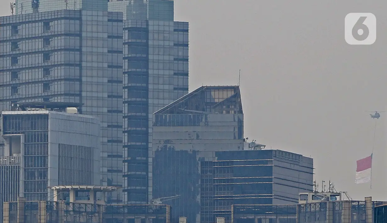 Bendera Merah Putih raksasa dikibarkan menggunakan helikopter TNI AU mengelilingi Jakarta, Jumat (13/8/2021). Pengibaran bendera yang dilakukan TNI AU sebagai bentuk latihan untuk persiapan puncak peringatan HUT ke-76 RI pada tanggal 17 Agustus 2021 mendatang. (Liputan6.com/Herman Zakharia)