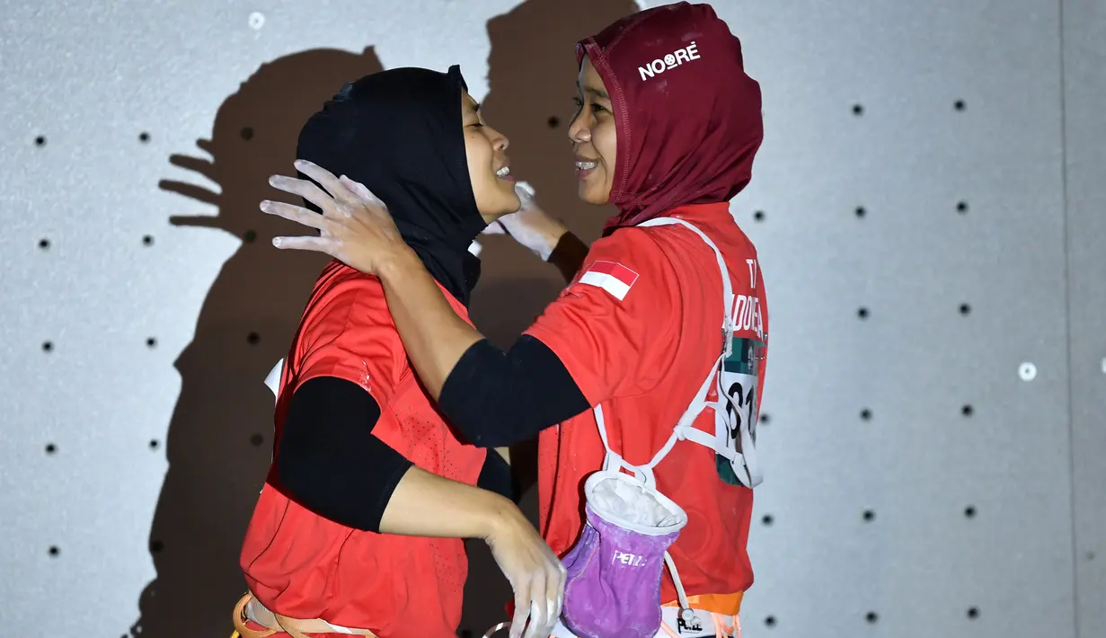 Peraih medali emas Indonesia Susanti Rahayu Aries berpelukan dengan peraih medali perak Puji Lestari usai pertandingan panjat tebing wanita Asian Games 2018 di Palembang (23/8). (AFP PHOTO / Adek Berry)