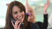 Duchess of Cambridge, Kate Middleton tertawa sambil menggenggam gagang telepon saat menjadi broker dalam acara amal tahunan ICAP di London, Inggris, Rabu (9/12/2015). (AFP PHOTO/POOL/JEREMY Selwyn)