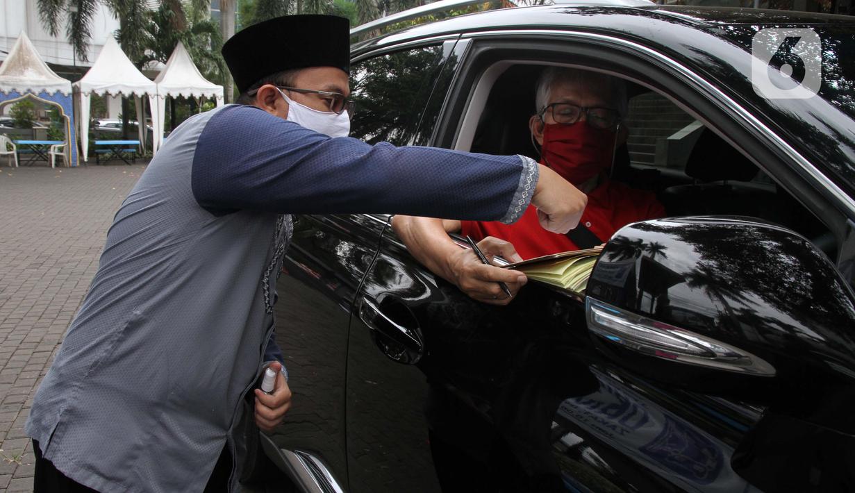Petugas Amil Zakat melayani warga yang membayar zakat fitrah melalui sistem "drive thru" di Masjid Nurul Hidayah, Tanah Kusir, Jakarta, Selasa (19/5/2020). Layanan zakat "drive thru" selama pandemi COVID-19 ini diberlakukan dengan protokol kesehatan dan keselamatan. (Liputan6.com/ Johan Tallo)