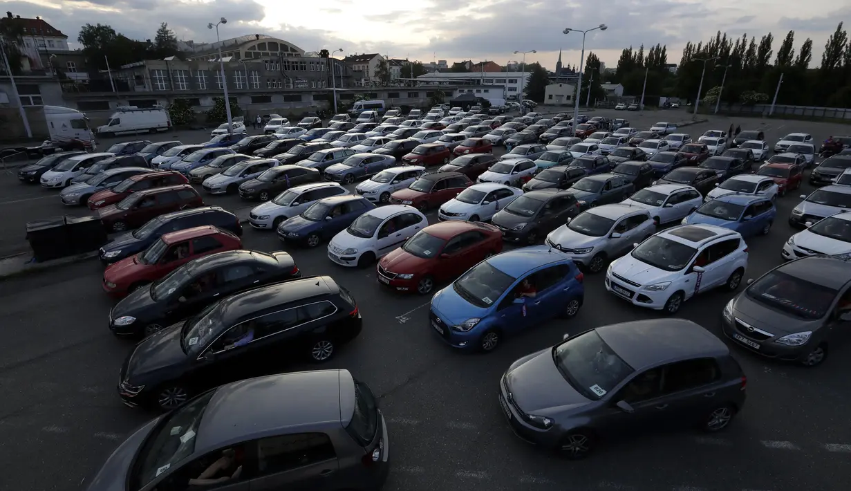 Suporter menyaksikan pertandingan Viktoria Plzen dan Sparta Praha dari dalam mobil di sebuah bioskop drive-in di Pilsen, Republik Ceko, Rabu (27/5/2020). Di tengah pandemi COVID-19, suporter Ceko dapat menyaksikan pertandingan bola lewat layar di bioskop drive-in. (AP Photo/Petr David Josek)