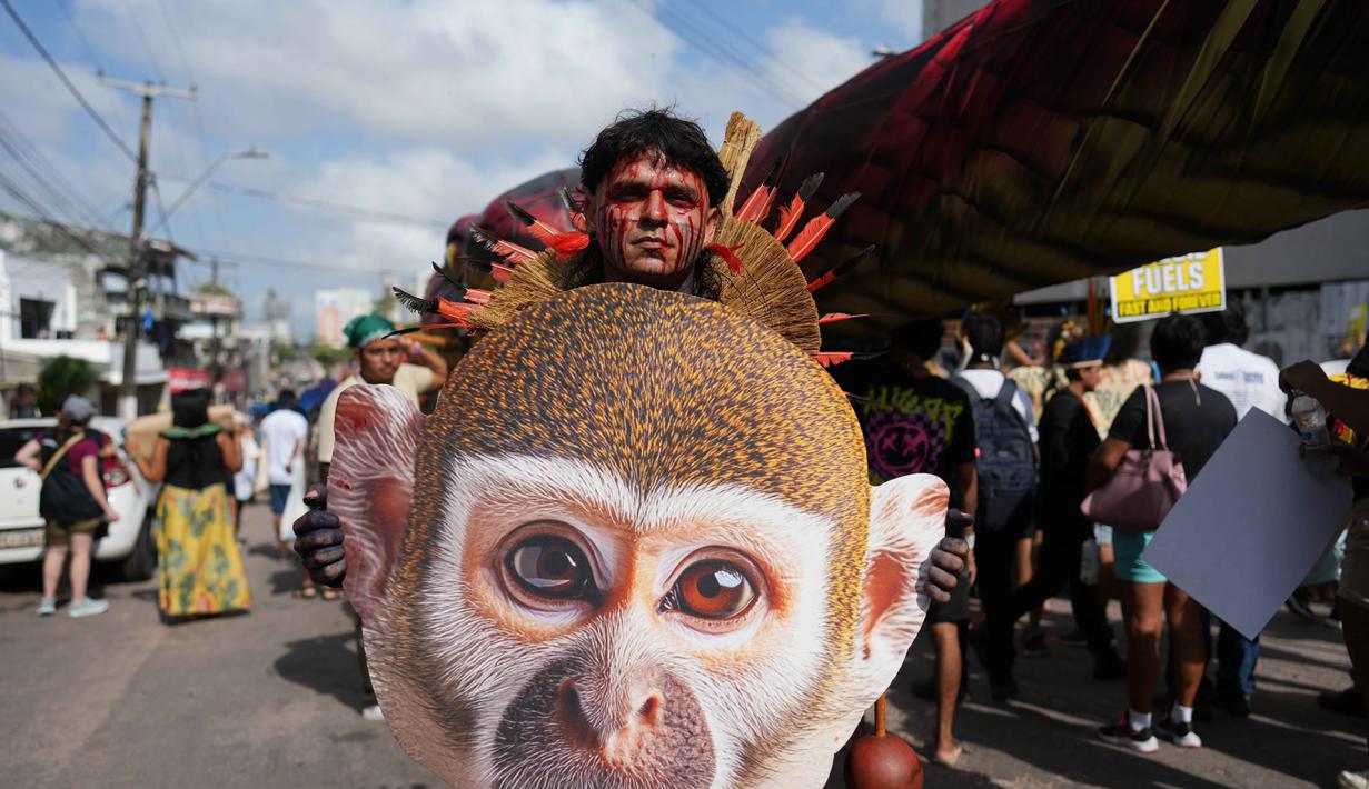Aksi protes ini juga menggarisbawahi ketegangan antara kebijakan lingkungan pemerintah Brasil dengan realita di lapangan, dimana komunitas adat di Brasil masih menghadapi ancaman dari perluasan agribisnis dan ekstraksi sumber daya. Tampak dalam foto, seorang aktivis asli membawa gambar seekor monyet di tengah-tengah perhelatan Konferensi Tingkat Tinggi Perubahan Iklim PBB (COP30), di Belem, Brasil, Senin 17 November 2025. (AP Photo/Andre Penner)