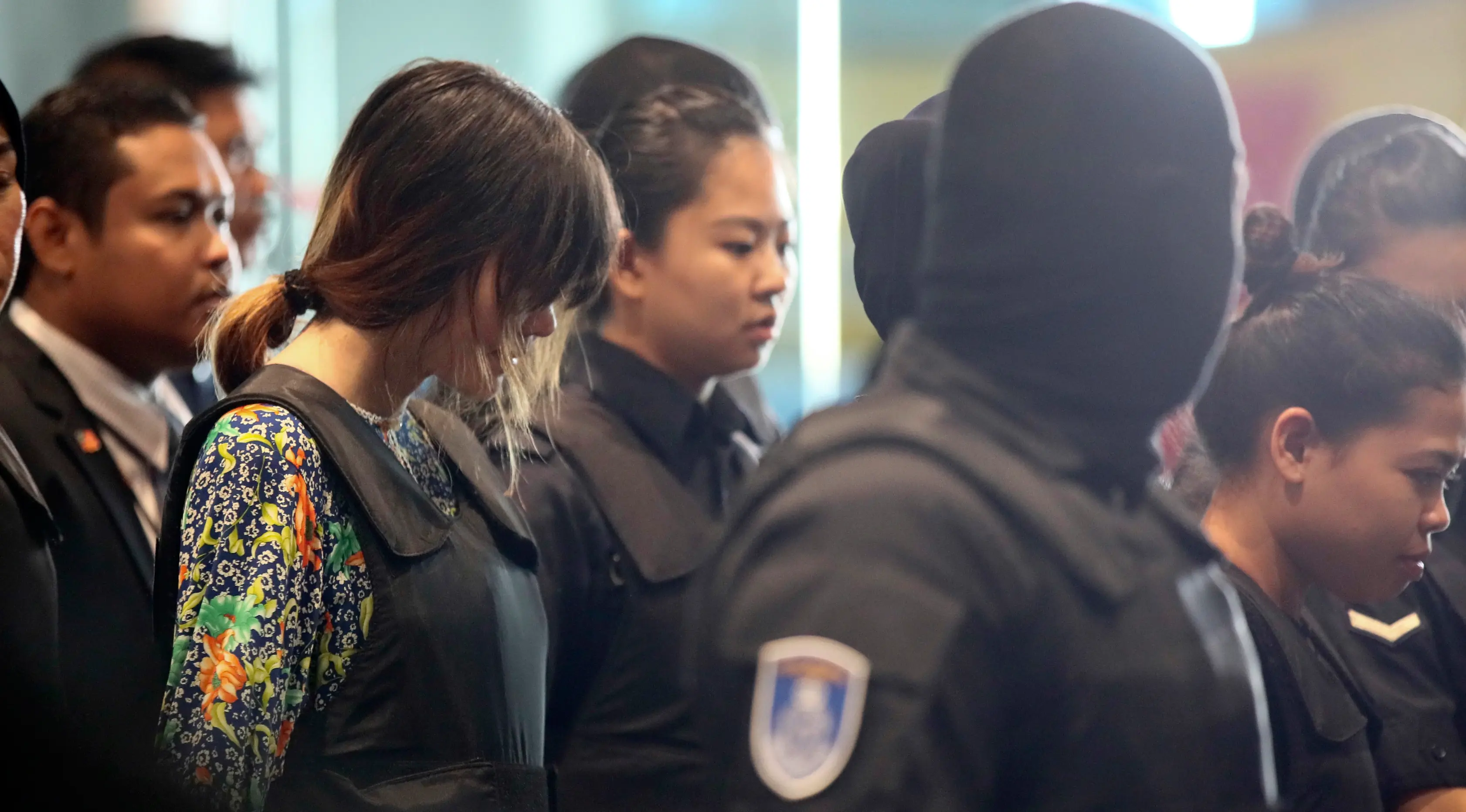 Tersangka kasus pembunuhan Kim Jong-nam, Siti Aisyah dan Doan Thi Huong, dikawal polisi menuju Bandara Internasional Kuala Lumpur, Selasa (24/10). Keduanya melakukan reka ulang kejadian di tempat keduanya dituding meracuni Kim Jong-nam. (AP/Sadiq Asyraf)