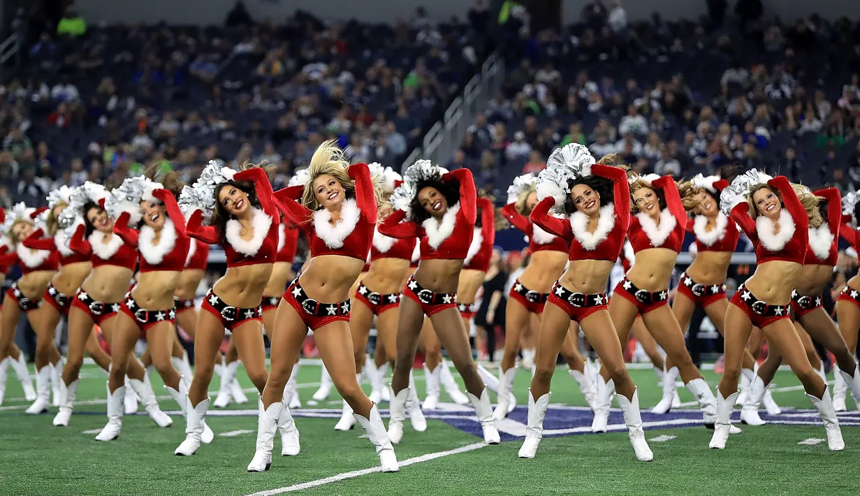 Sejumlah pemandu sorak (cheerleader) Cowboys Dallas berkostum santa claus menghibur penonton saat tim Cowboys Dallas istirahat pada pertandingan Seattle Seahawks di AT & T Stadium, Texas (24/12). (AFP / Getty Images / Tom Pennington)