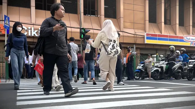 Warga melintasi pelican crossing yang kini sudah terpasang di Stasiun Cikini, Jakarta Pusat.