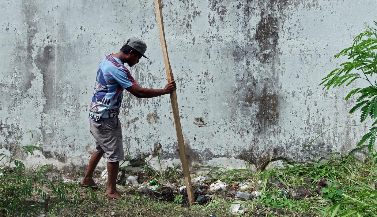 Seorang pria memasukkan kayu ke dalam lubang yang digunakan narapidana untuk kabur dari Lapas Kerobokan, Bali, Senin (19/6). Empat narapidana asing kabur melalui lubang sepanjang 15 m yang mengarah ke parit di luar bangunan Lapas. (AP /Firdia Lisnawati)