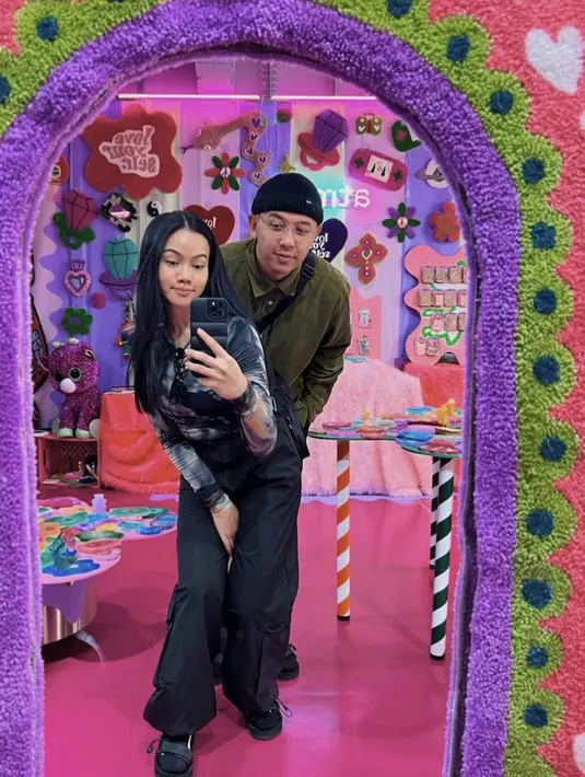 Bersama sang suami yang mengenakan jaket hijau, Yura tampil dengan long sleeve warna abstrak dipadukan celana hitamnya. Yura membiarkan rambut panjangnya terurai, lagi-lagi wajahnya pun tampil natural. Credit: Instagram (@yurayunita)