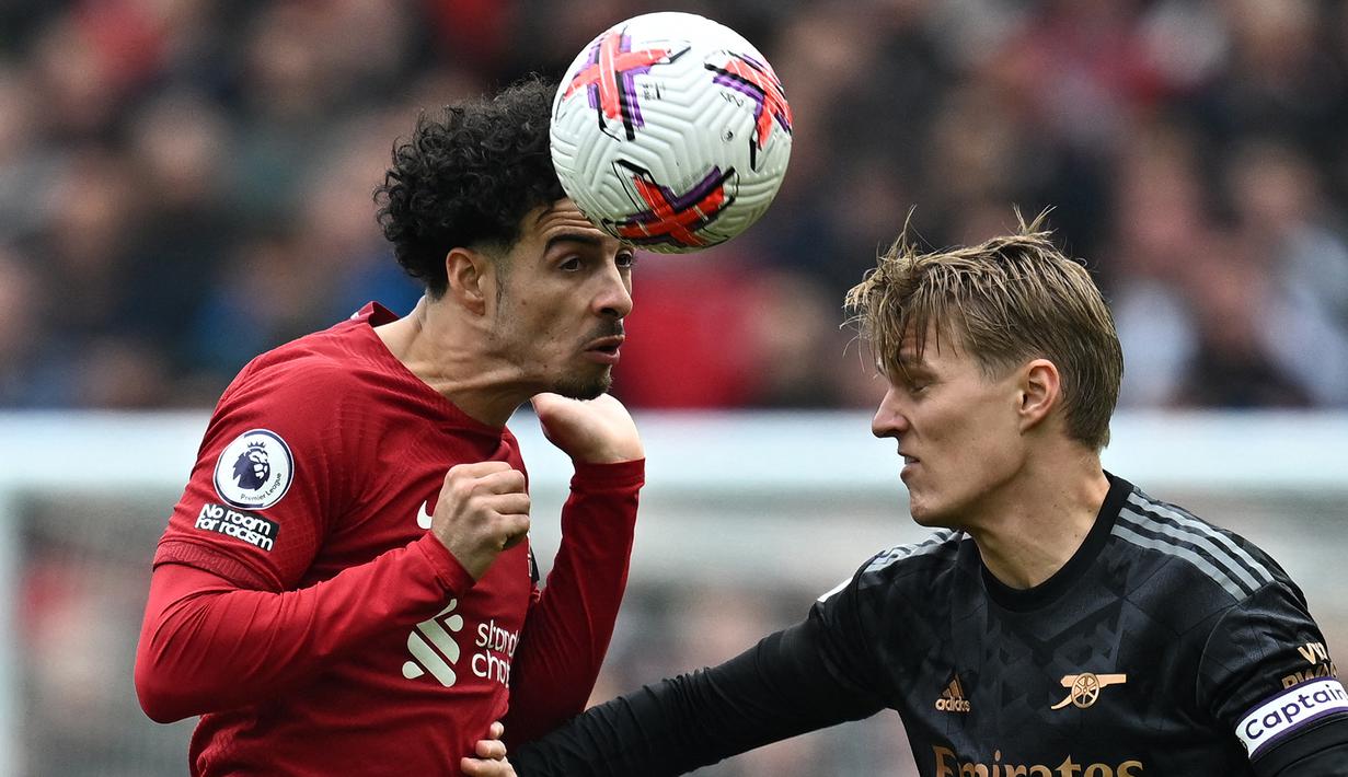 Gelandang Liverpool, Curtis Jones (kiri) memenangi duel udara dengan gelandang Arsenal, Martin Odegaard pada laga lanjutan pekan ke-30 Liga Inggris 2022/2023 di Anfield Stadium, Liverpool, Minggu (9/4/2023) malam WIB. (AFP/Paul Ellis)