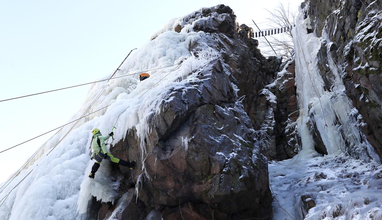 Aksi seorang perempuan memanjat dinding es buatan di desa Vir, Republik Ceko, Minggu (14/2/2021). Ketika suhu turun di Republik Ceko, pemanjat tebing memanfaatkan kondisi beku dengan mengubah permukaan batu menjadi dinding es setinggi 20 meter untuk pendaki. (AP Photo/Petr David Josek)