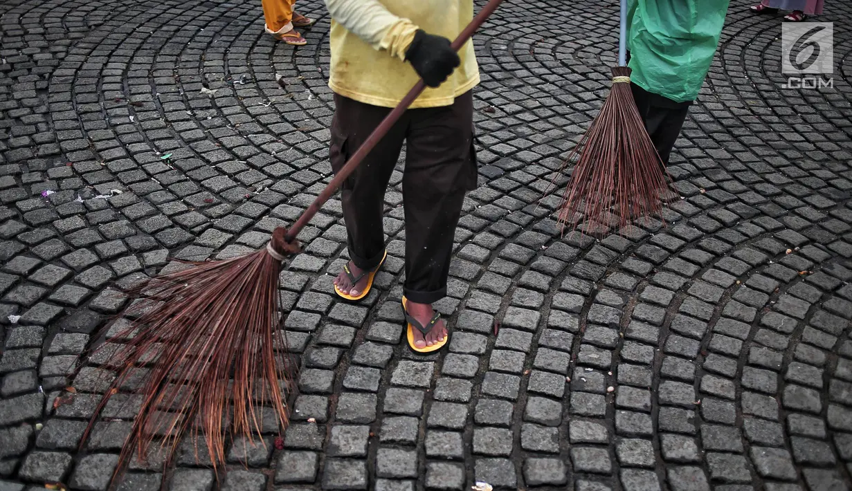 Petugas kebersihan membersihkan sisa sampah usai perayaan Tahun Baru 2019 di Monas, Jakarta, Selasa (1/1). Total sampah di DKI Jakarta saat perayaan Tahun Baru 2019 mencapai 327 ton. (Liputan6.com/Faizal Fanani)