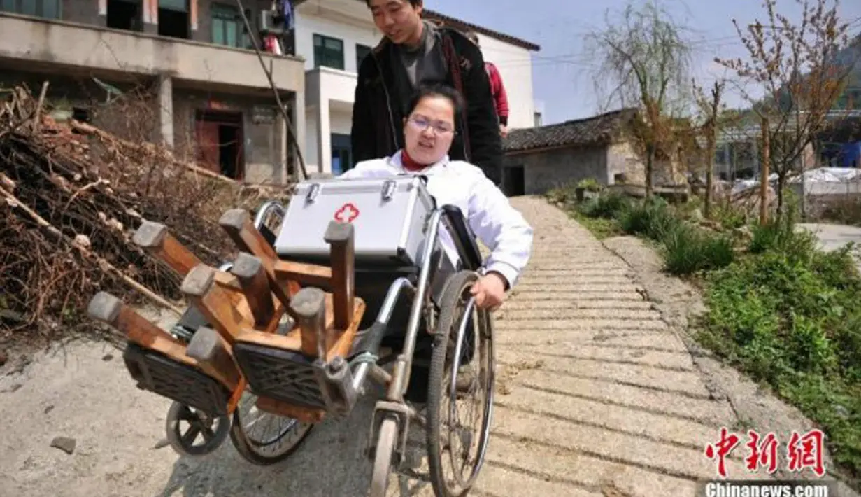 Li Juhong didorong menggunakan kursi roda di Chongqing, Cina. Selama 15 tahun terakhir ia berhasil membantu masyarakat desa yang sakit dengan berprofesi sebagai dokter, untuk menyiasatinya, ia menggunakan bangku kayu sebagai "kaki" nya. (Chinanews.com)