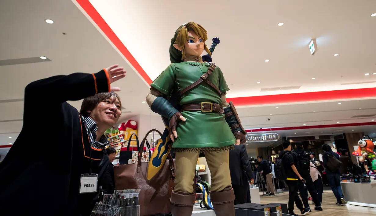 Seorang lelaki berpose di sebelah Link, salah satu karakter Legend of Zelda, permainan legendaris dari Nintendo selama pratinjau pers di toko baru Nintendo di Tokyo, 19 November 2019. Nintendo akan meresmikan toko pertamanya di ibu kota Jepang tersebut pada pekan ini. (Behrouz MEHRI/AFP)