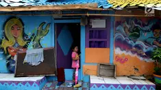 Seorang anak berdiri di depan pintu rumah dengan warna-warni cat dinding dan grafiti di Kampung Bekelir, Babakan Kota Tangerang, Jumat (16/11). Kampung ini dihuni sekitar 300 KK. (Liputan6.com/Fery Pradolo)