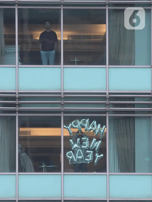 Tamu berdiri di jendela salah satu kamar hotel yang dipasangi tulisan “Happy New Year” di Bundaran HI, Jakarta, Kamis (31/12/2020). Hotel menjadi alternatif bagi warga yang untuk merayakan pergantian malam Tahun Baru. (merdeka.com/Imam Buhori)