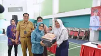 Ketua Tim Penggerak (TP) PKK Surabaya Rini Indriyani secara simbolis membagikan seragam dan sepatu sekolah kepada sejumlah perwakilan pelajar penerima. (Istimewa)