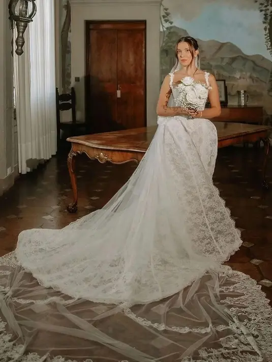 Untuk upacara pemberkatan, Brown kenakan gaun Galia Lahav dengan detail renda. Ia memadukan gaun dengan veil tipis dan aksesori yang minimalis [@milliebobbybrown]