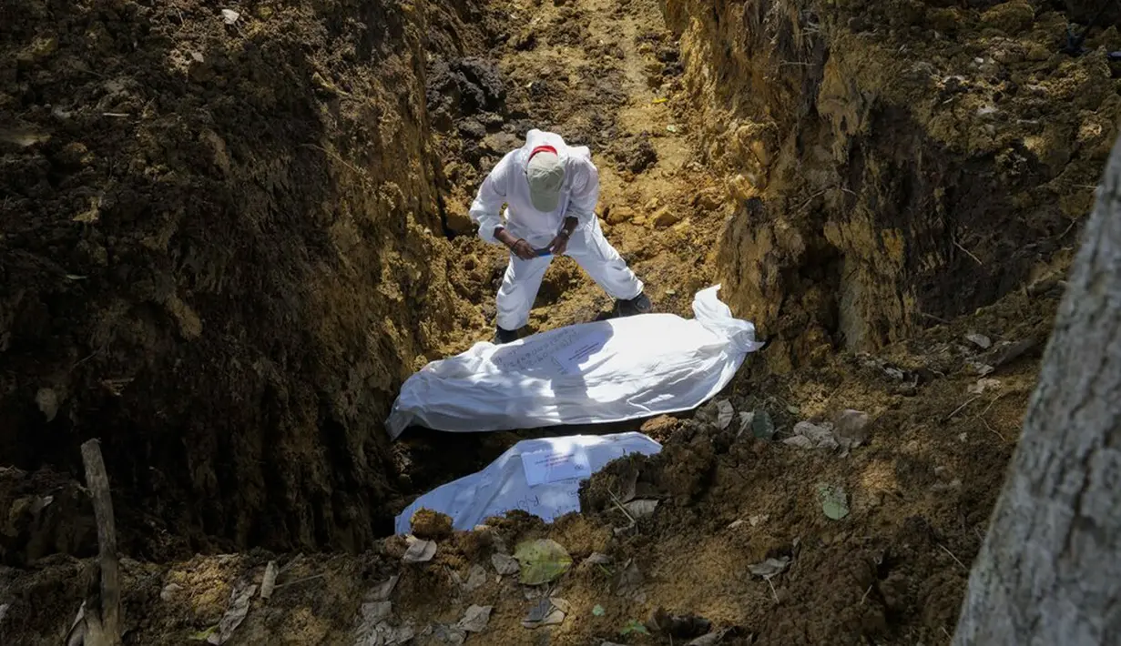 Seorang anggota tim forensik mengambil foto jenazah sekelompok imigran yang tewas saat mencoba menyeberangi Celah Darien di Pemakaman Guayabillo, Agua Fria, Panama, 30 September 2021. Celah Darien berupa lembah dan rawa-rawa di Amerika Tengah yang memutus Jalan Pan Amerika. (AP Photo/Arnulfo Franco)