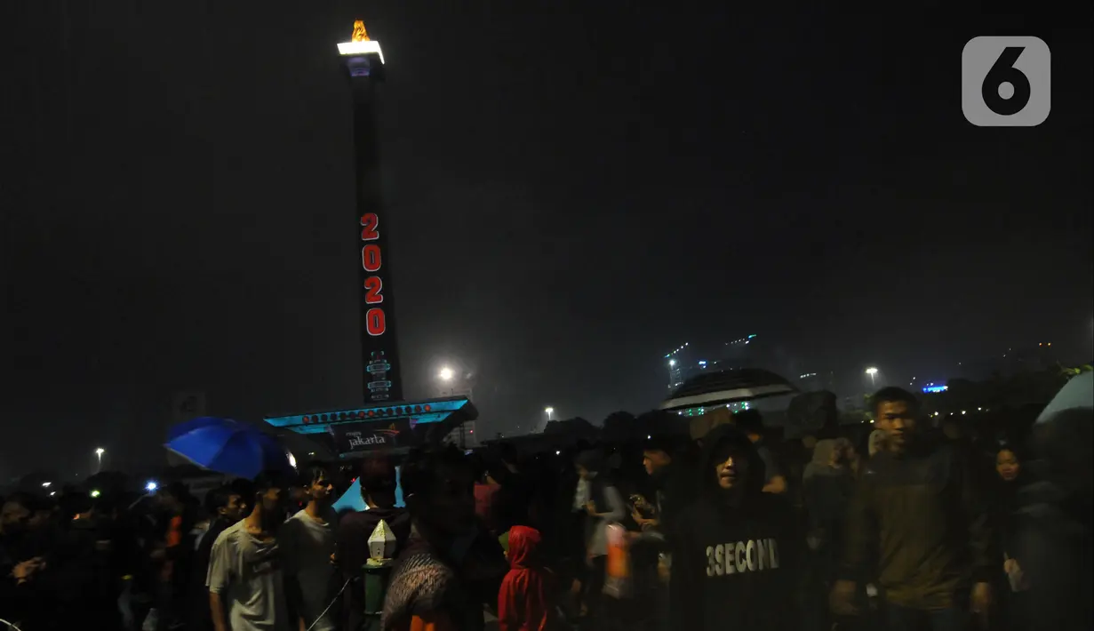 Pengunjung memadati kawasan Monumen Nasional saat malam pergantian tahun, Jakarta, Rabu (1/1/2020). Penampilan video mapping mewarnai kemeriahan malam pergantian tahun baru di kawasan Monumen Nasional, Jakarta. (Liputan6.com/Helmi Fithriansyah)
