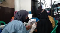 Tenaga medis menyuntikkan vaksin Covid-19 kepada salah seorang calon penumpang bus di Terminal Induk Kota Bekasi, Rabu (22/9/2021). (Liputan6.com/Bam Sinulingga)