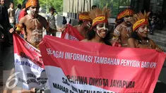 Sejumlah pemuda Papua mengenakan pakaian adat membawa spanduk berunjuk rasa di depan Gedung KPK, Jakarta, Senin (19/12). Mereka meminta KPK mengusut kasus korupsi pejabat yang mencalonkan diri pada Pilkada Jayapura 2017. (Liputan6.com/Helmi Affandi)
