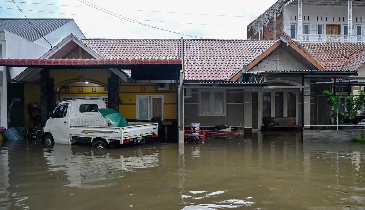 Selain banjir, hujan deras disertai angin kencang juga menyebabkan insiden lain, seperti pohon tumbang di beberapa ruas jalan di Darul Imarah, yang memerlukan evakuasi oleh pihak berwenang. Tampak dalam foto, rumah-rumah yang terendam banjir akibat hujan deras di kawasan permukiman Darul Imarah, pinggiran Banda Aceh, pada Kamis 27 November 2025. (CHAIDEER MAHYUDDIN/AFP)