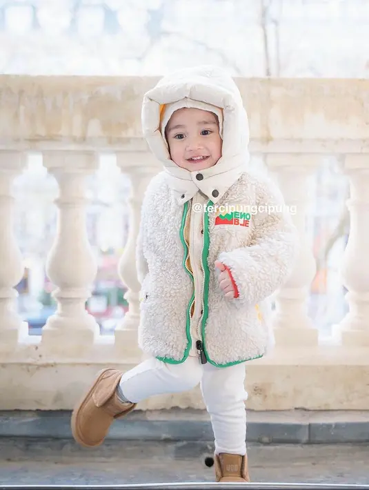 Ia juga tampil serba putih dengan hoodie puff, jaket berbulu, dan celananya. Dipadukan sepatu coklatnya. [@tercipungcipung]