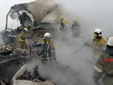 Petugas pemadam kebakaran Kyrgyz berhasil memadamkan api diantara sisa-sisa pesawat kargo Turki yang jatuh di daerah perumahan di Bishkek, Kyrgyzstan (16/1). (AP Photo/Vladimir Voronin)