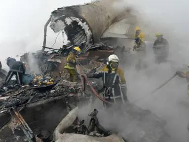 Petugas pemadam kebakaran Kyrgyz berhasil memadamkan api diantara sisa-sisa pesawat kargo Turki yang jatuh di daerah perumahan di Bishkek, Kyrgyzstan (16/1). (AP Photo/Vladimir Voronin)