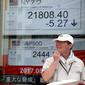 Seorang pria berdiri didepan indikator saham elektronik sebuah perusahaan sekuritas di Tokyo (29/8). Ketegangan politik yang terjadi karena Korut meluncurkan rudalnya mempengaruhi pasar saham Asia. (AP Photo/Shizuo Kambayashi)