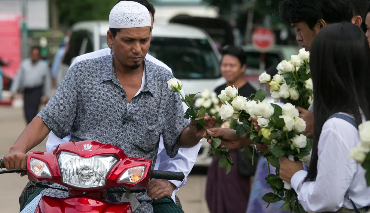 Umat Buddha Myanmar membagikan mawar putih kepada umat Islam yang akan melaksanakan salat Id pada perayaaan Idul Fitri di kota Than Lyin, pinggiran Yangon, Rabu (5/6/2019). Relawan berbaris di luar masjid dan memberikan bunga itu kepada jemaah yang merayakan Idul Fitri. (Sai Aung MAIN/AFP)