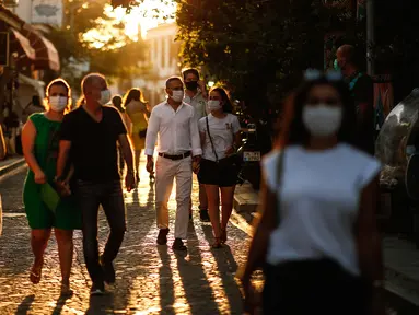 Turis yang mengenakan masker untuk melindungi dari penyebaran virus corona berjalan di kota Ayvalik di Laut Aegea, Turki, Rabu (9/9/2020). Turki telah mewajibkan penggunaan masker di semua lokasi selain di rumah, menyusul lonjakan jumlah infeksi COVID-19. (AP Photo/Emrah Gurel)