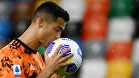 Striker Juventus, Cristiano Ronaldo, mencium bola saat melawan Udinese pada laga Liga Italia di Dacia Arena, Minggu (2/5/2021). Juventus menang dengan skor 1-2. (AFP/Marco Bertorello)
