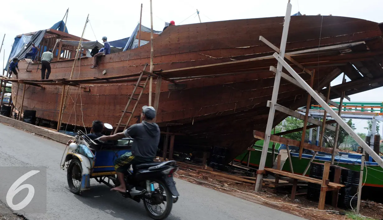Warga melintas di area pembuatan perahu di Balongan, Indramayu, Jawa Barat, Jumat (15/1/2016). Dibutuhkan waktu selama delapan bulan untuk menyelesaikan satu unit perahu yang dijual seharga Rp.4 miliar - Rp.5 miliar tersebut. (Liputan6.com/Helmi Afandi)