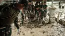 Personel Tentara Nasional Indonesia (TNI) dari YONIF TP 853/BRB, Aceh Timur, membersihkan lumpur di Rumah Sakit Daerah di Aceh Tamiang, pada Selasa 16 Desember 2025, setelah banjir bandang sekitar tiga minggu lalu. Lumpur tebal di banyak lorong dan genangan air dampak banjir bandang yang masih menutup sebagian besar dari Rumah Sakit Daerah Aceh Tamiang. (Yasuyoshi Chiba/AFP)