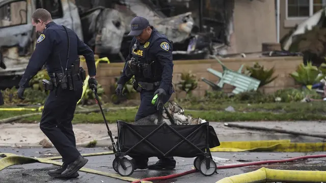Kendaraan dan rumah rusak setelah sebuah pesawat jatuh di kawasan permukiman San Diego, AS. Membakar beberapa rumah Kamis dini hari, 22 Mei 2025. (AP/Gregory Bull)