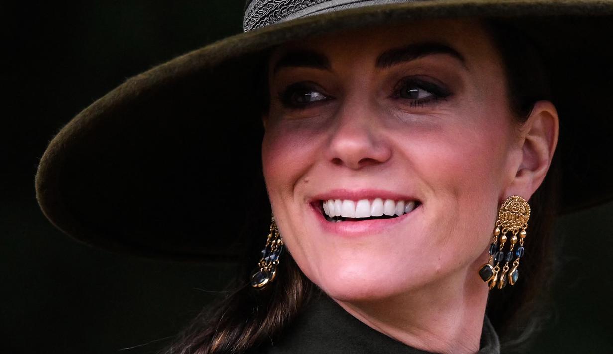 Kate Middleton, Princess of Wales dari Inggris tersenyum usai kebaktian Natal di Sandringham, Norfolk, Inggris pada 25 Desember 2022. Ibu tiga anak ini tampak bergaya dalam balutan coat hijau olive panjang yang bagian bawahnya lebar dari koleksi Alexander McQueen. (AFP/Daniel Leal)