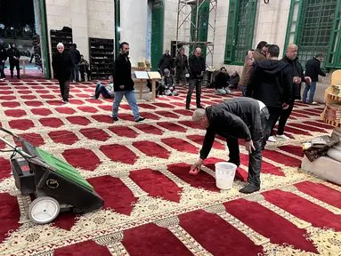 Para pria membersihkan masjid Al-Aqsa di Kota Tua Yerusalem menyusul bentrokan antara jamaah Palestina dan pasukan keamanan Israel selama bulan suci Ramadan pada 5 April 2023. (AFP/Ahmad Gharabli)