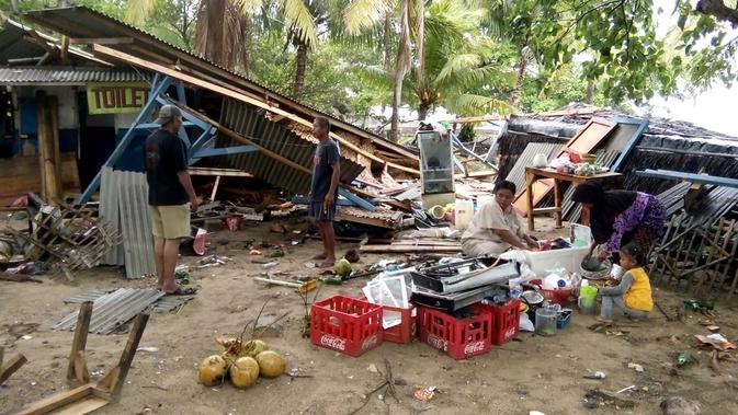 Warga mengumpulkan barang-barang dari bangunan yang rusak setelah tsunami menerjang Pantai Carita, di perairan Banten, Minggu (23/12). Tsunami menerjang pantai di Selat Sunda, khususnya di daerah Pandenglang, Lampung Selatan, dan Serang. (SEMI / AFP)