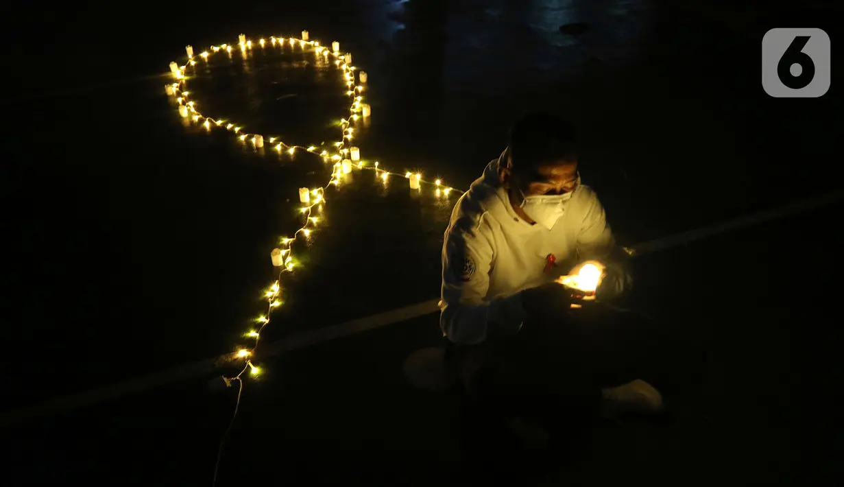 Seorang relawan menyalakan lampu pada malam renungan Hari AIDS Sedunia di Tanah Abang, Jakarta, Rabu (1/12/2021). Acara ini digelar secara gabungan oleh lembaga dan relawan pendamping orang dengan HIV/AIDS (ODHA). (Liputan6.com/Herman Zakharia)