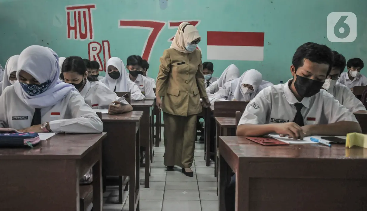Guru mengawasi murid saat kegiatan Pembelajaran Tatap Muka (PTM) 100 Persen di SMP Negeri 9 Depok, Cipayung, Jawa Barat, Senin (24/1/2022). Pemerintah Kota Depok hari ini mulai menggelar PTM 100 persen secara serentak untuk tingkat TK, SD, dan SMP. (merdeka.com/Iqbal S Nugroho)