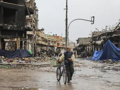 Seorang warga Palestina berjalan di Kota Gaza pada hari keempat gencatan senjata sementara antara Hamas dan Israel, Senin (27/11/2023). (AP Photo/Mohammed Hajjar)