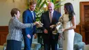 Pangeran Harry dan Meghan Markle bereaksi ketika menerima hadiah sepatu bayi dari istri Gubernur Jenderal Australia, Lady Lynne di Sydney, Selasa (16/10). Meghan yang sedang hamil muda tampak senang menerima hadiah bayi pertamanya (Phil Noble/Pool via AP)